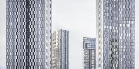 Four high-rise towers rise in a muted sky  