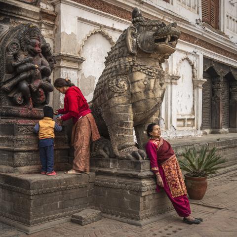 2 ladies and a young person worshiping a statue in Bhaktapur Durbar Square