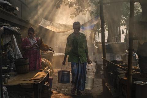 Man walking through early morning streets with 2 buckets