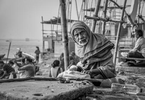 one man pauses, his gaze distant and reflective, as others gather along the banks of the Mother Ganges