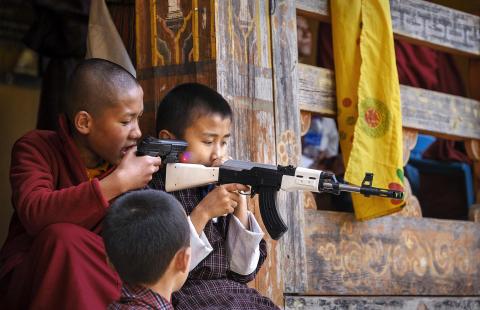 2 boys holding fake guns in the streets of Bhutan