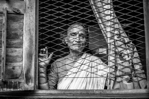 Lady looking outside a window with a grate