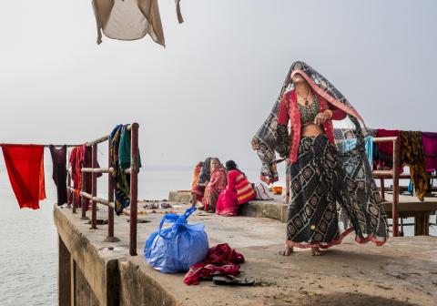 A lady walking around a pier with hanging clothes 