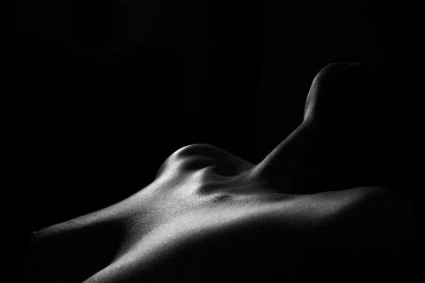Top part of a female body in dark surroundings laying. 