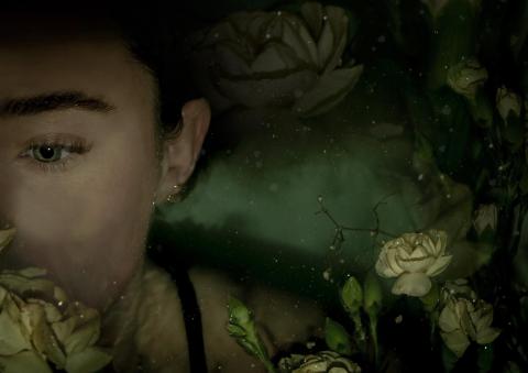 A face in green surroundings with flowers