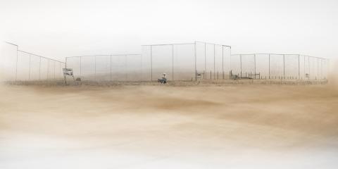 A dusty baron landscape except walls of concrete in the distance 