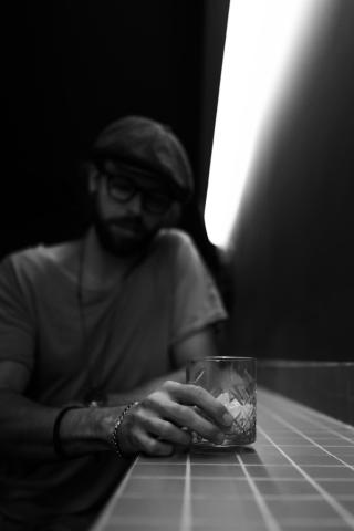 A man sitting in a dark bar with a drink